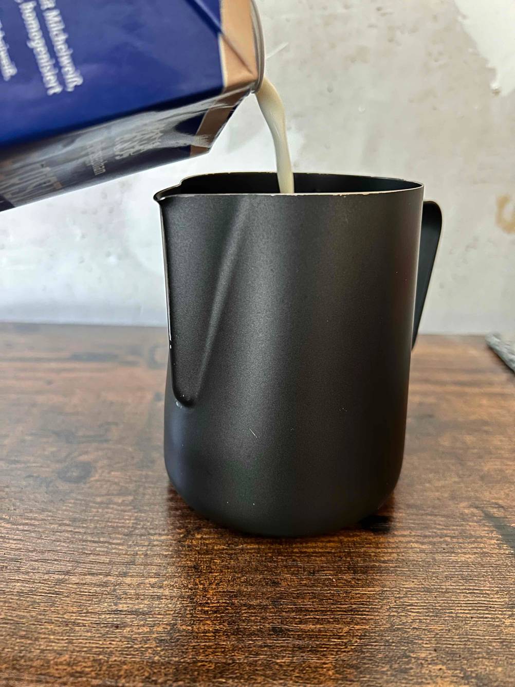 Schwarzes Milchkännchen, in das Milch eingefüllt wird.