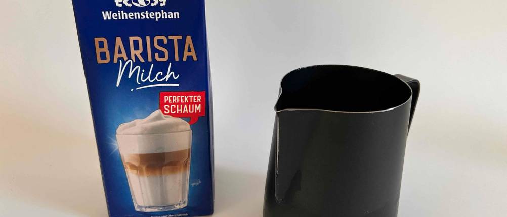 Milchkännchen neben einer Packung Milch.