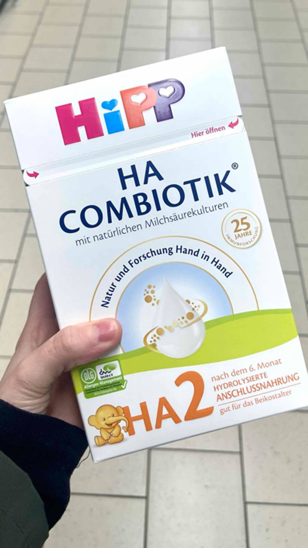 Eine Hand hält eine Packung 2er Milchnahrung zum testen.