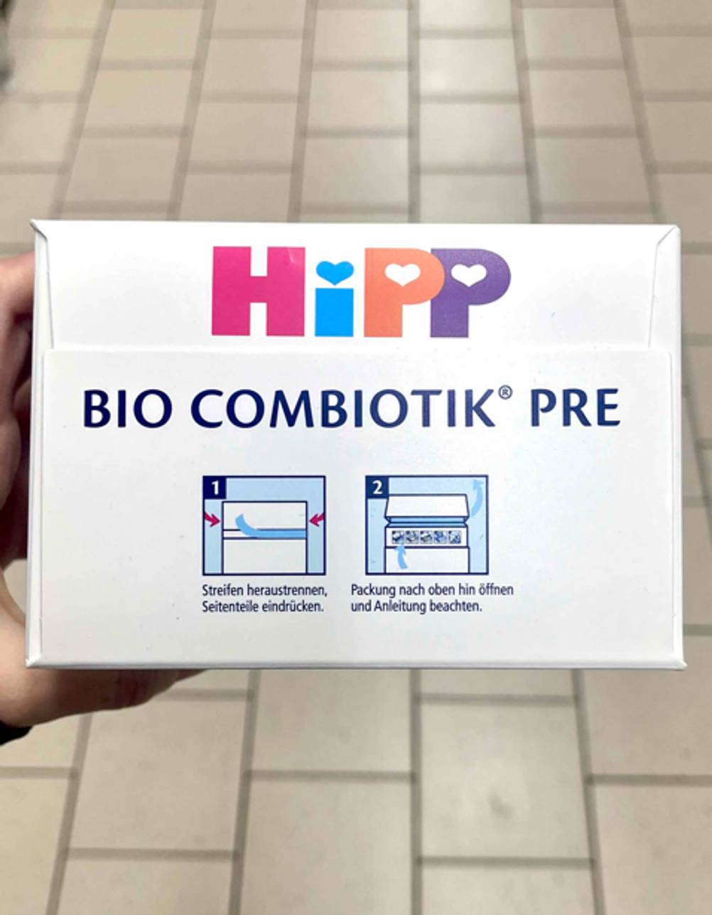 Milchnahrung im Test: Auf der Oberseite einer Packung ist eine bebilderte Anleitung zum öffnen.