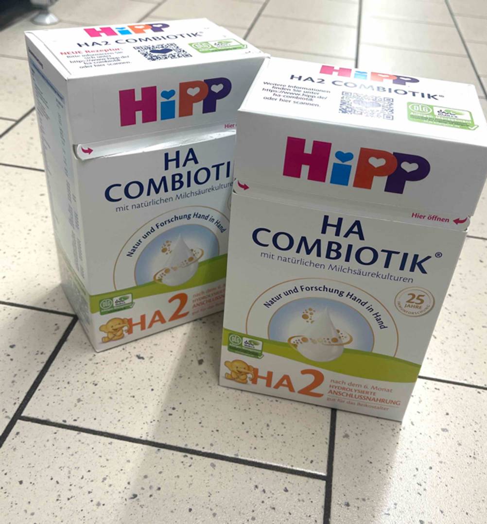 Zwei Packungen Milchnahrung stehen zum testen auf einem Fliesenboden.