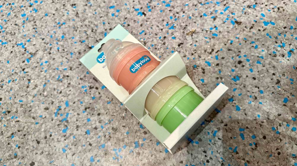 Auf einem grau-blauen Boden liegt ein Milchpulver-Portionierer im Test.