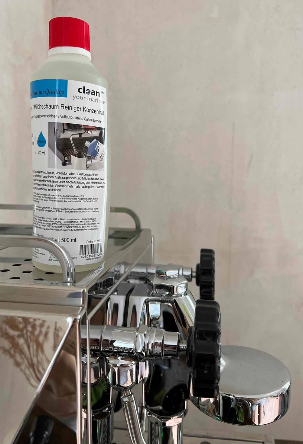 Eine Flasche des getesteten Milchsystemreinigers steht auf einer Kaffeemaschine.