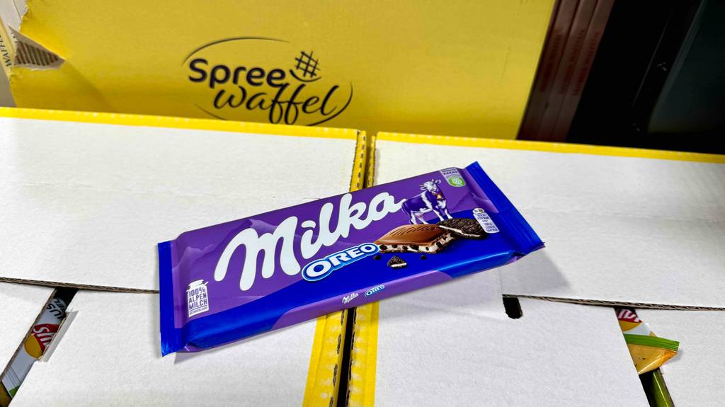 Eine Tafel Milka-Schokolade liegt zum Testen auf einem Karton mit anderen Süßigkeiten.