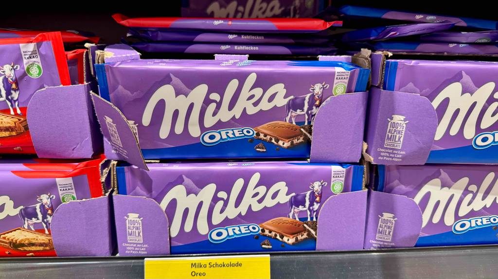Milka-Schokolade im Test: Mehrere Tafeln verschiedener Sorten stehen gestapelt in einem Regal.