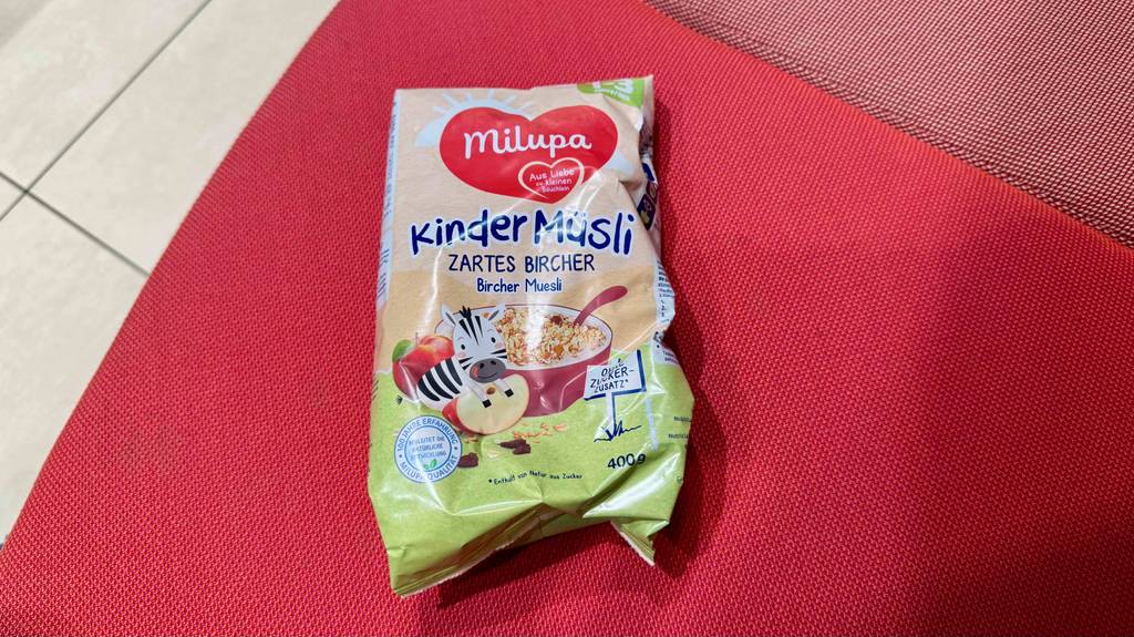 Eine Packung Kindermüsli liegt zum Testen auf einem roten Tuch.