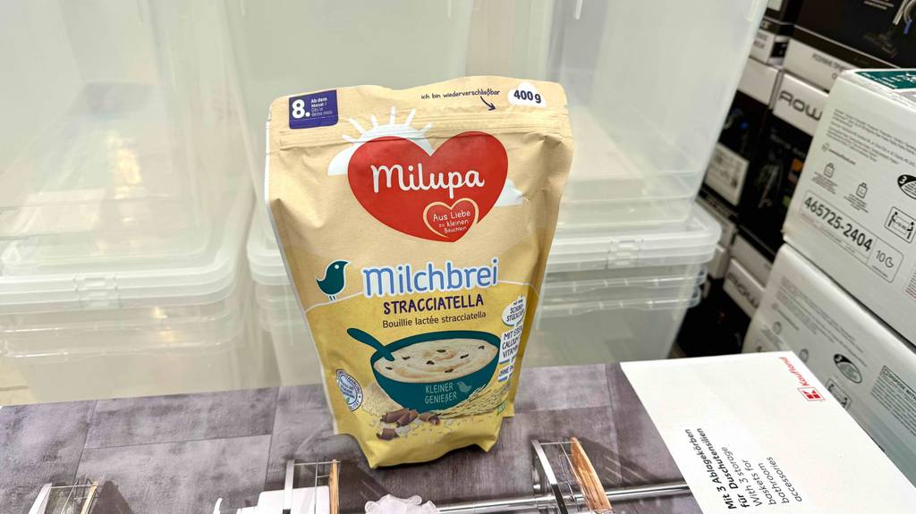 Ein getesteter Milchbrei in der 400-g-Tüte der Marke Milupa steht auf einem Karton im Verkaufsbereich.