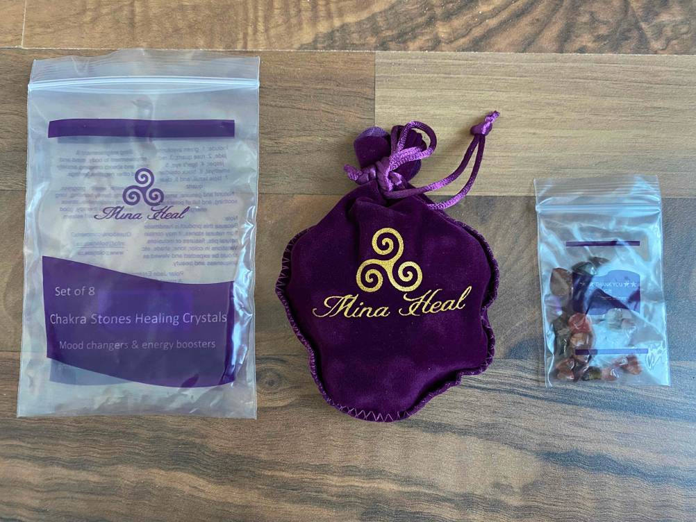 Im Test: Heilsteine von Mina Heal mit Originalverpackung und Zubehör auf einem Holzboden.