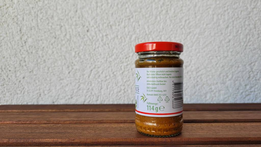 Blick auf Inhaltsangaben der gelben Currypaste Ming Chu im Glas.