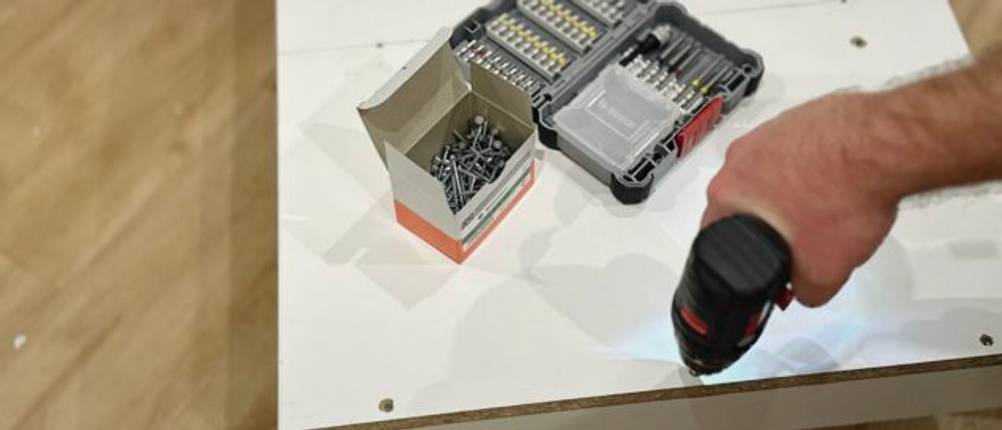 Mit dem Mini-Akkuschrauber von Bosch werden Schrauben in eine Spanplatte geschraubt.