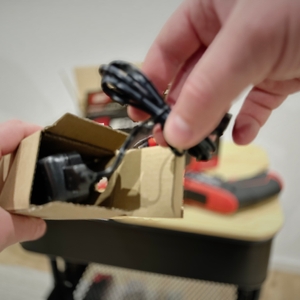 Der Ladeadapter des Einhell-Mini-Akkuschraubers wird aus dem Karton entnommen.