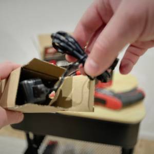 Der Ladeadapter des Einhell-Mini-Akkuschraubers wird aus dem Karton entnommen.