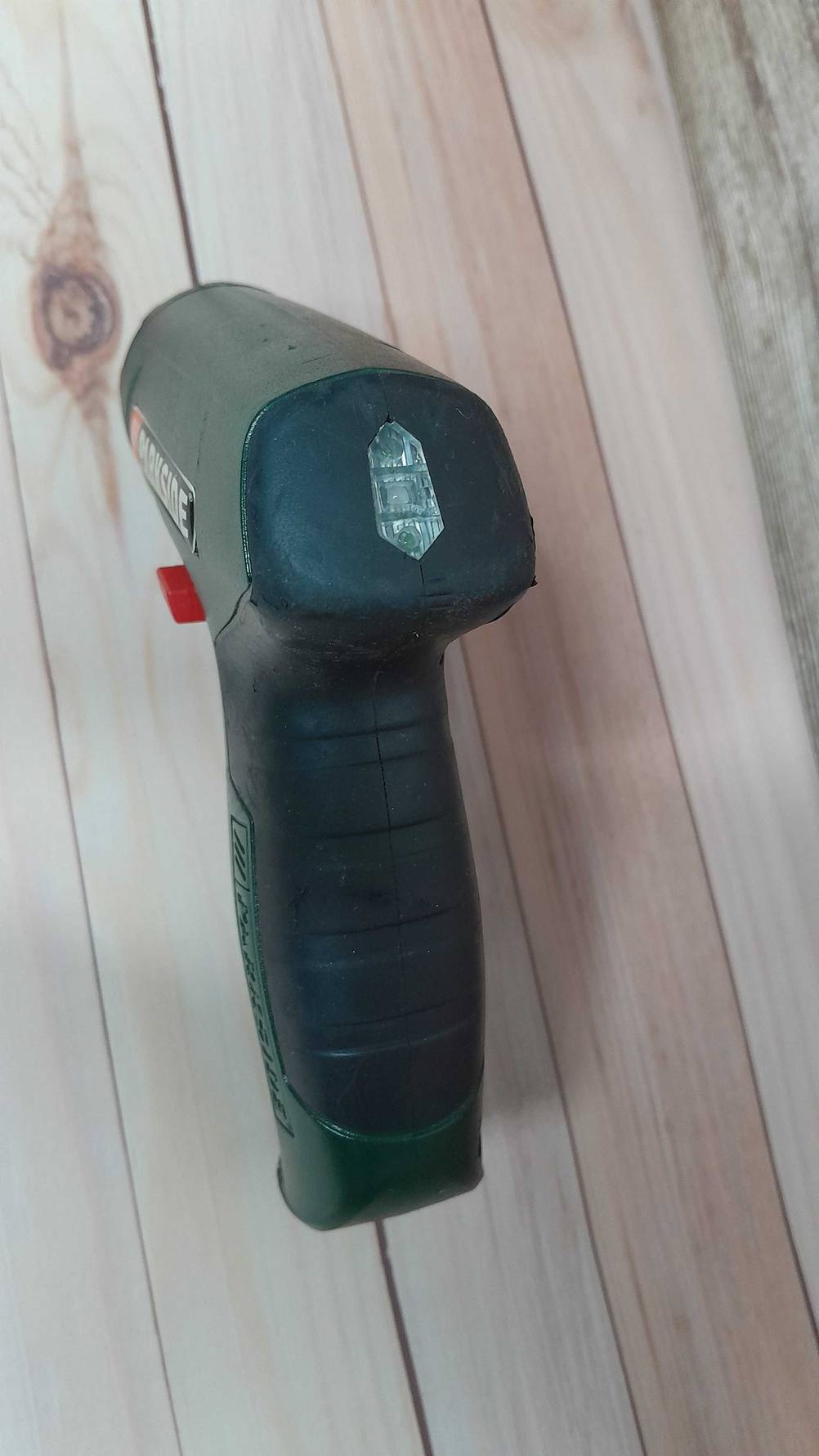Rückseite eines getesteten Mini-Akkuschraubers auf einer Holzfläche.