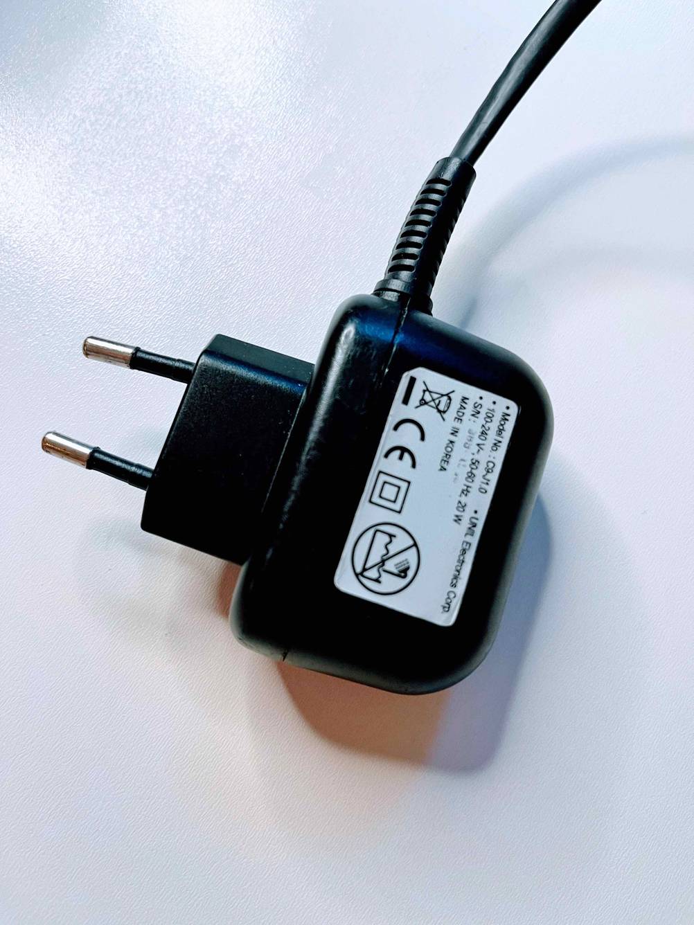 Nahaufnahme des Stromsteckers eines getesteten Mini-Glätteisens auf einer hellen Fläche.