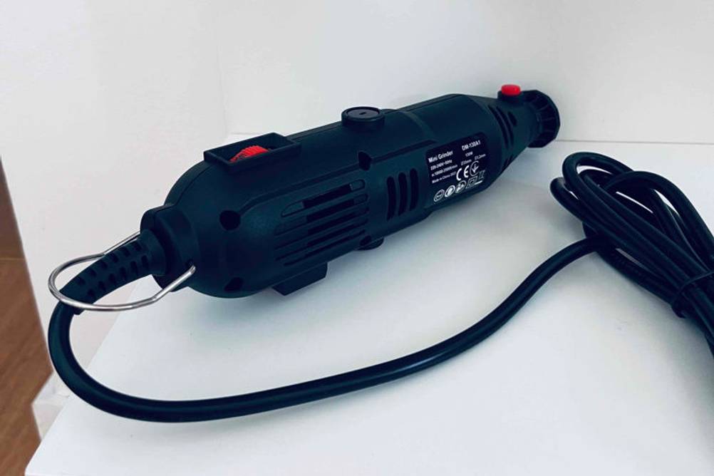 Gesamtansicht eines getesteten Multischleifers der Marke Mini Grinder, der sich auf einer weißen Oberfläche befindet.