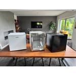 Drei Mini-Kühlschränke stehen nebeneinander auf einem Tisch.