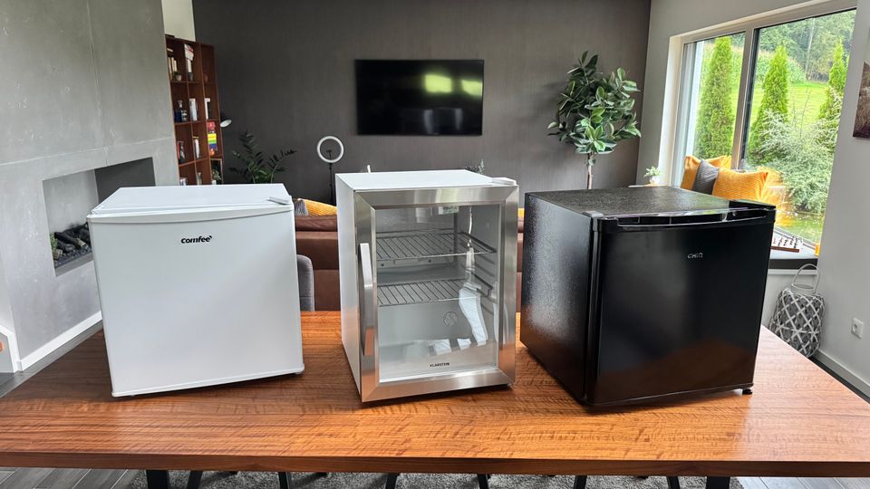 Drei Mini-Kühlschränke stehen nebeneinander auf einem Tisch.
