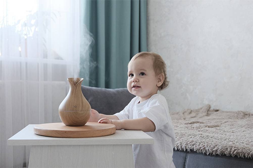 Mini-Luftbefeuchter im Test: Ein Baby, das vor einem Tisch mit einem Luftbefeuchter steht.