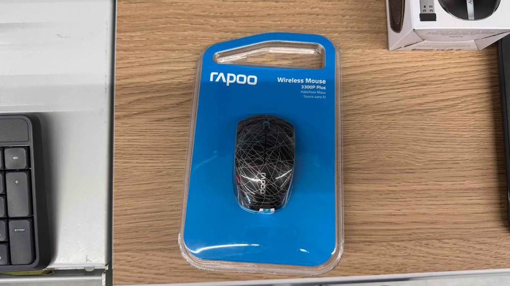 Auf einem Bürotisch liegt eine verpackte Mini-Maus im Test.