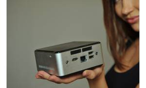 Eine Frau hält einen getesteten lüfterlosen Mini-PC in der ausgestreckten Hand.