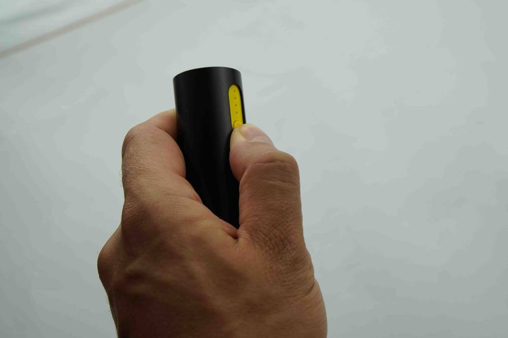 Nahaufnahme wie ein Daumen auf den Power-Kopf einer getesteten Mini-Powerbank drückt.