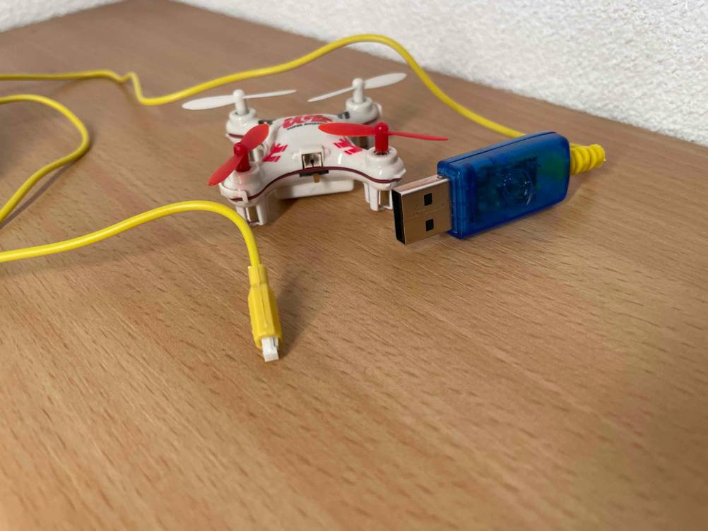 Mini-Quadrocopter getestet: Das Gerät mit USB-Kabel auf einer Holzfläche.