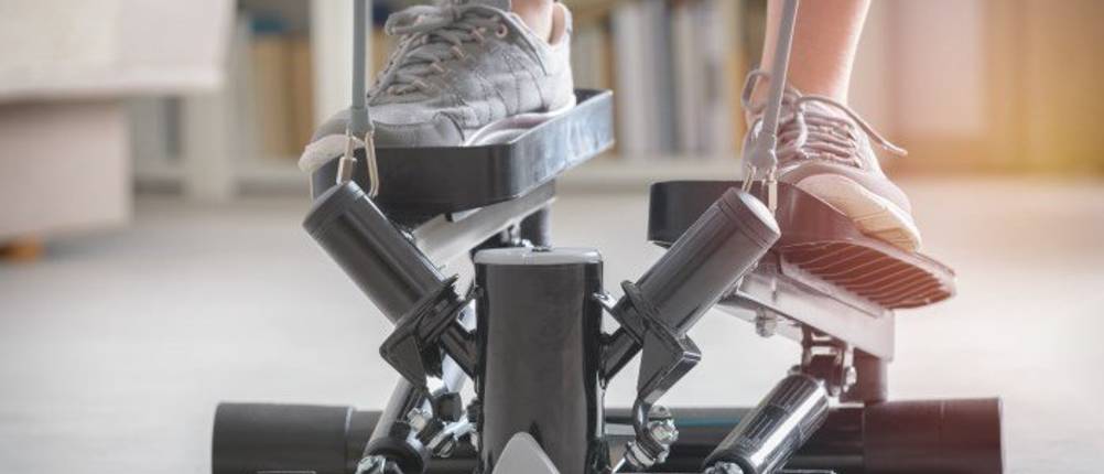 Swing-Stepper im Test: Eine Frau trainiert auf einem Swing-Stepper mit Bändern. Man sieht nur ihre Beine in Sportschuhen.