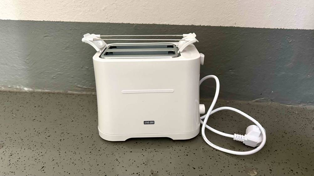 Der Mini-Toaster im Test vor einer Wand auf dem Boden stehend.