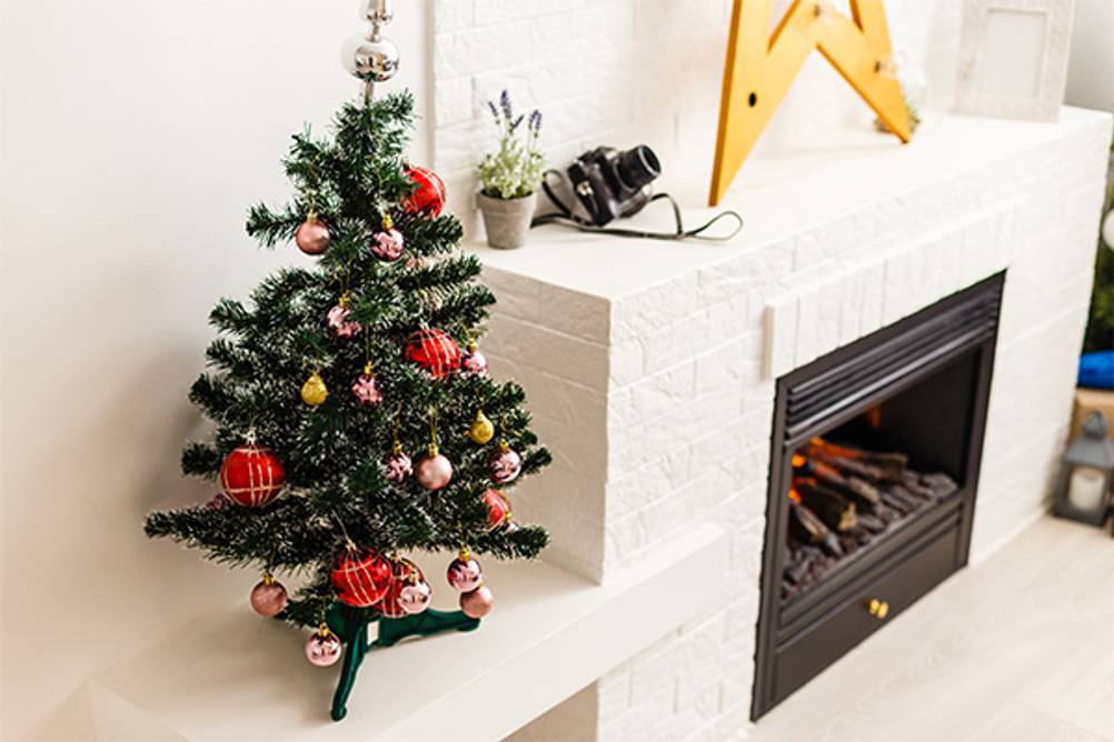 Mini-Weihnachtsbaum im Test: Ein künstlicher kleiner Weihnachtsbaum auf einer Ablage neben einem Kamin