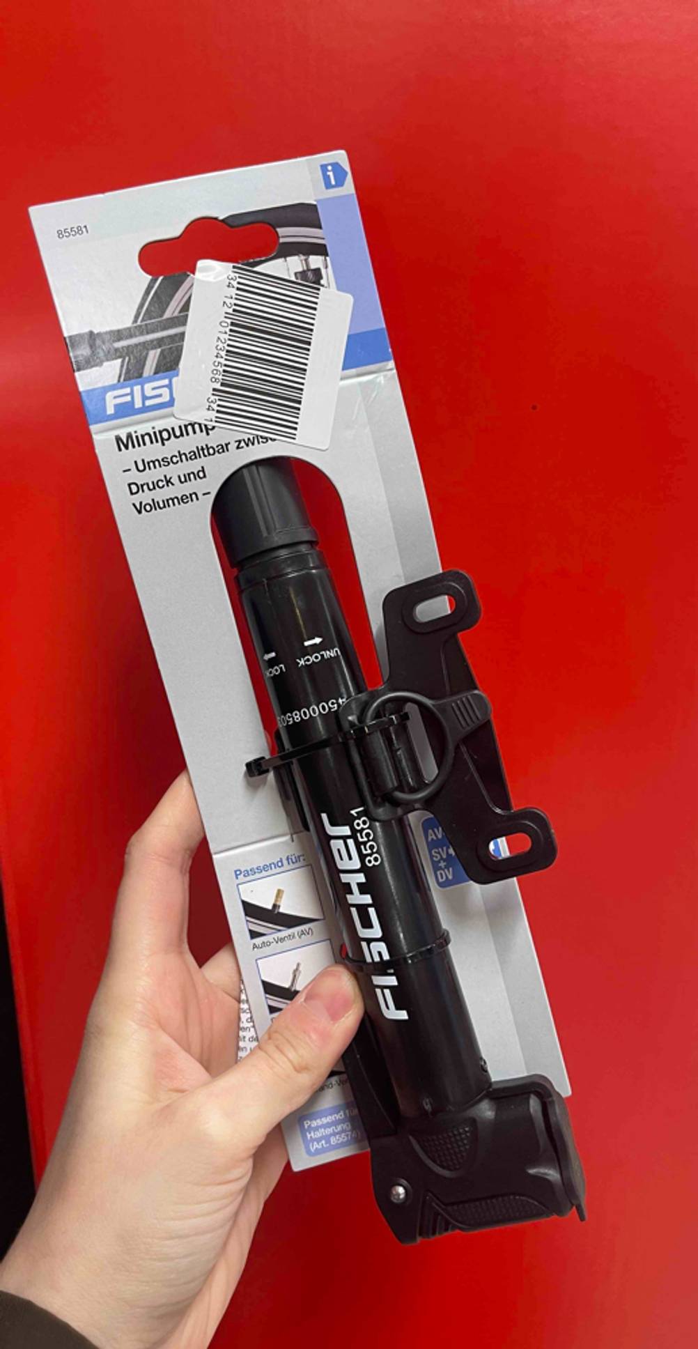 Eine Hand hält die getestete Minipumpe vor eine rote Wand.