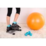Mini-Stepper-Test: Eine Person trainiert auf einem Mini-Stepper neben zwei blauen Hanteln und einem Gymnastikball. 