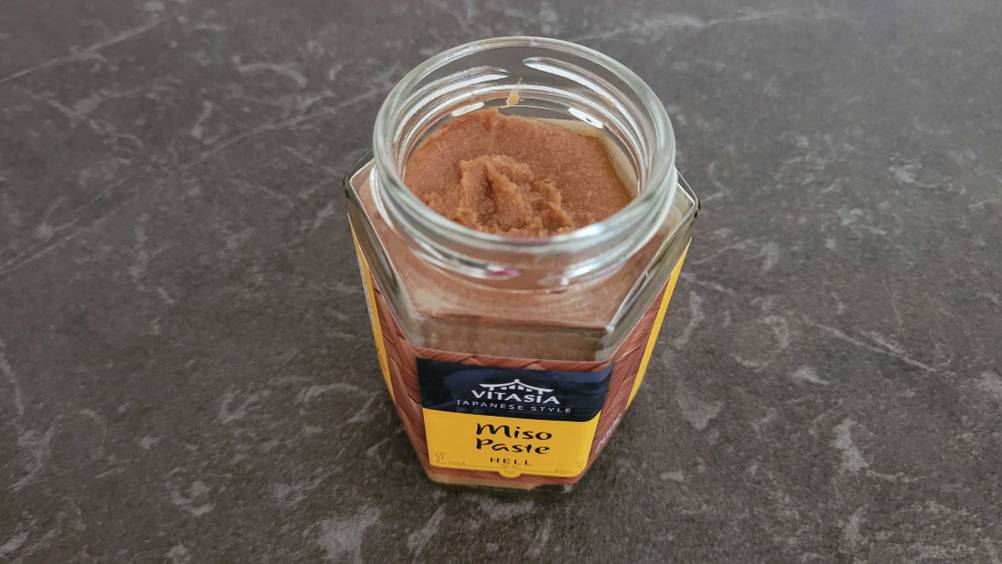 Ein offenes Glas der getesteten Miso-Paste auf einem dunklen Tisch.
