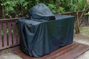 Ein im Freien stehender Gasgrill ist mit einer Abdeckung geschützt