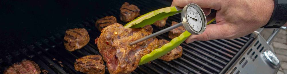 Grillfleisch wird mittels Grillzange und Fleischthermometer geprüft.