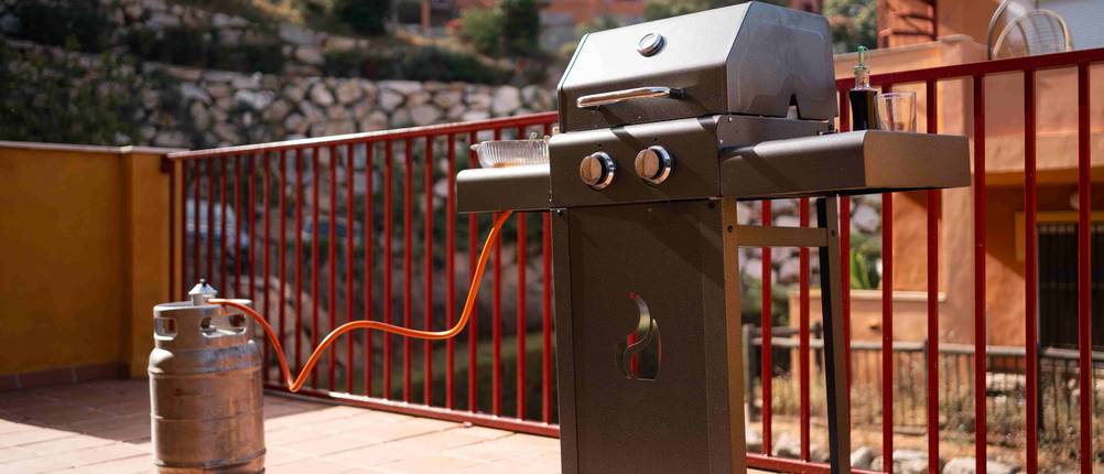 Gasgrill steht auf einer Terrasse.
