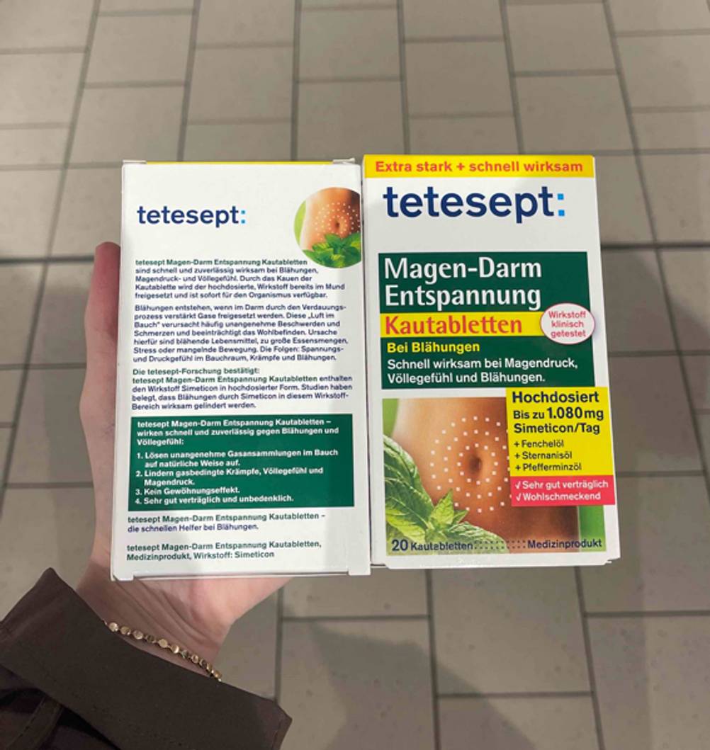 Im Test: Eine Hand hält zwei Packungen Mittel gegen Blähungen, eine mit der Rückseite nach oben.