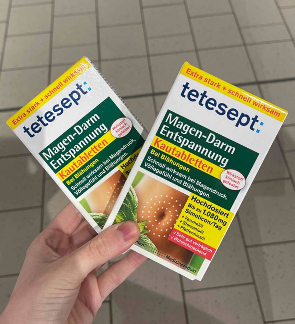 Mittel gegen Blähungen im Test: Eine Hand hält zwei Packungen überkreuzt.