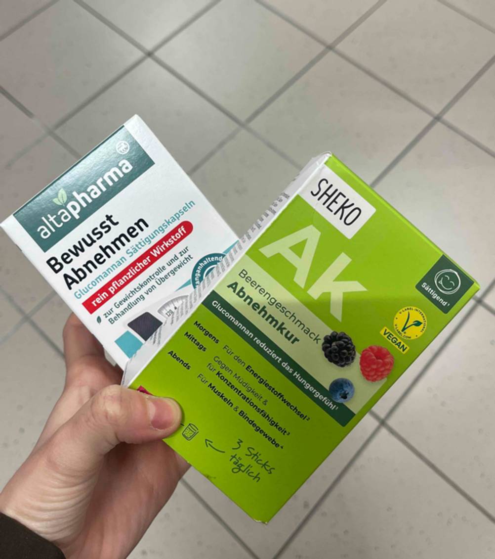 Eine Hand hält zwei unterschiedliche Verpackungen mit den getesteten Mitteln zum Abnehmen.