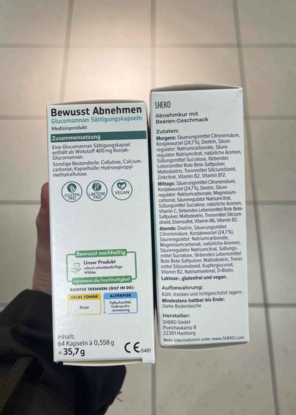 Eine Hand hält zwei unterschiedliche Verpackungen, der Fokus liegt bei beiden auf den aufgedruckten Zusammensetzungen. Die Packungen enthalten die Abnehm-Mittel im Test.
