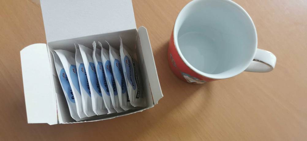Brennnesseltee getestet: Neben einer leeren Tasse befindet sich eine geöffnete Packung Brennnesseltee mit einzelnen Päckchen.