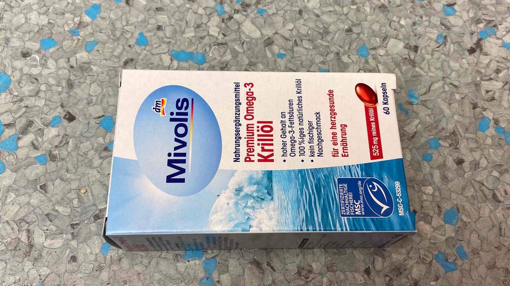Krillöl im Test: ein Verpackungskarton mit 60 Kapseln von Mivolis liegt auf grau gesprenkeltem Hintergrund.