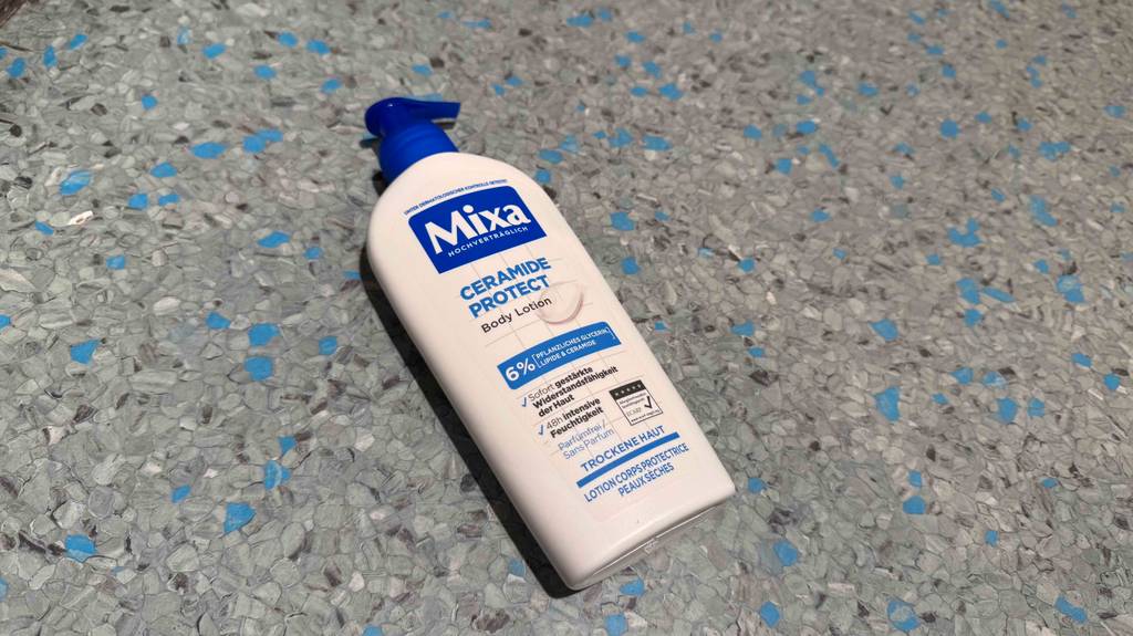 Eine Spender-Flasche mit getesteter Bodylotion für trockene Haut liegt auf einem Linoleumboden.