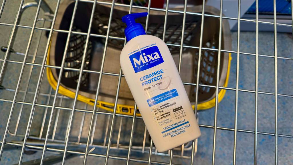 Eine Spender-Flasche der Marke Mixa mit Bodylotion für trockene Haut im Test liegt in einem Einkaufskorb.