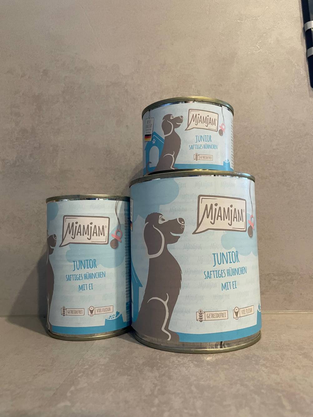 MjAMjAM-Hundefutter getestet: Drei unterschiedlich große Dosen des Futters vor einer grauen Fläche.