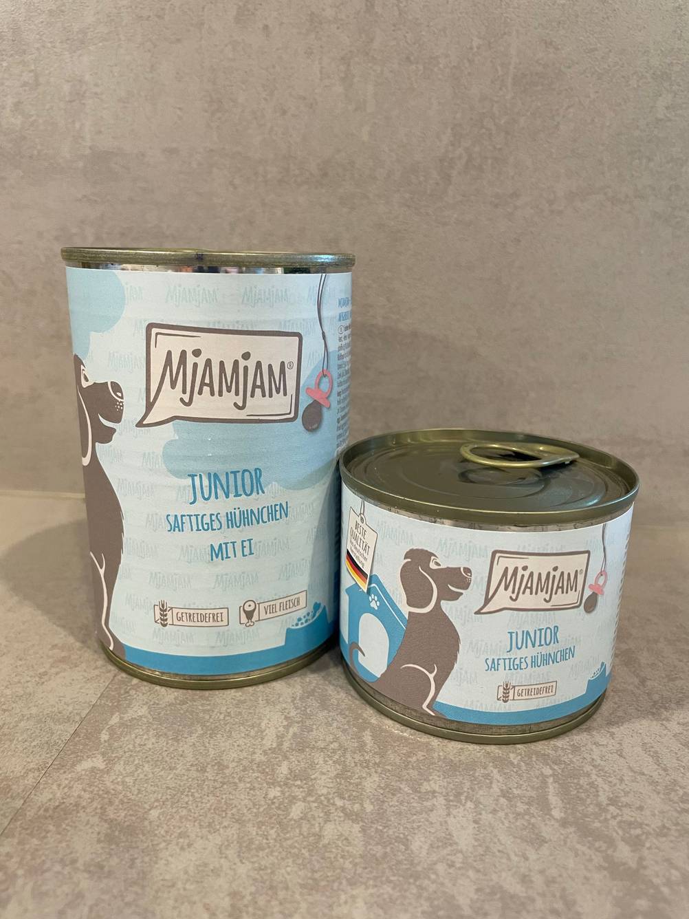 Zwei unterschiedlich große Dosen des getesteten MjAMjAM-Hundefutters auf einer grauen Fläche.