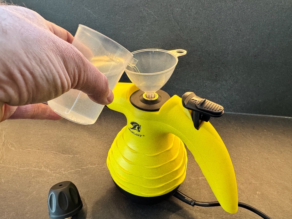 Eine Hand füllt Wasser in den Tank des Mlmlant-Handgerät-Dampfreiniger