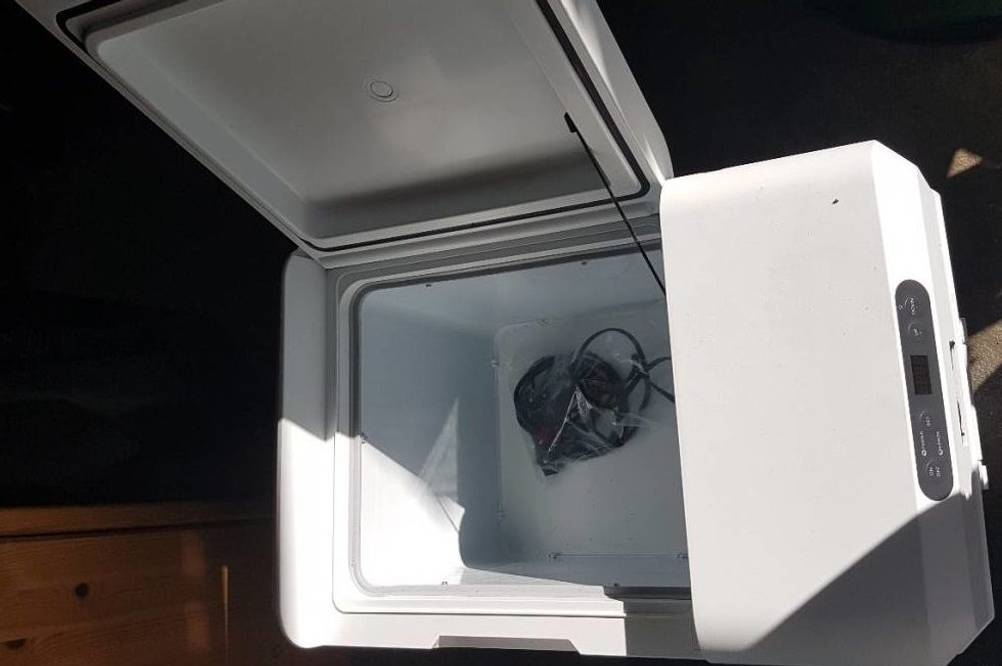Nahaufnahme einer weißen Kompressor-Kühlbox im Test, inklusive Temperaturanzeige und Kabel im Inneren, geöffnet vor dunklem Hintergrund