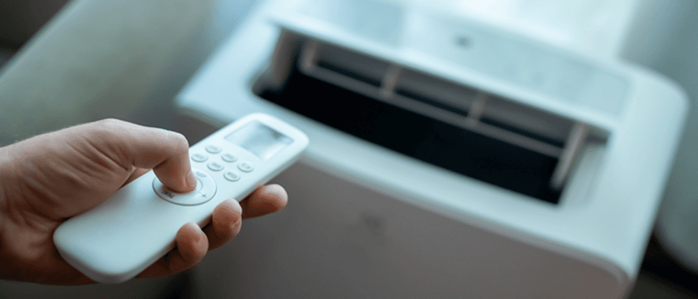 Mobile Split-Klimaanlage im Test: Eine Person bedient ein Klimagerät mit einer Fernbedienung