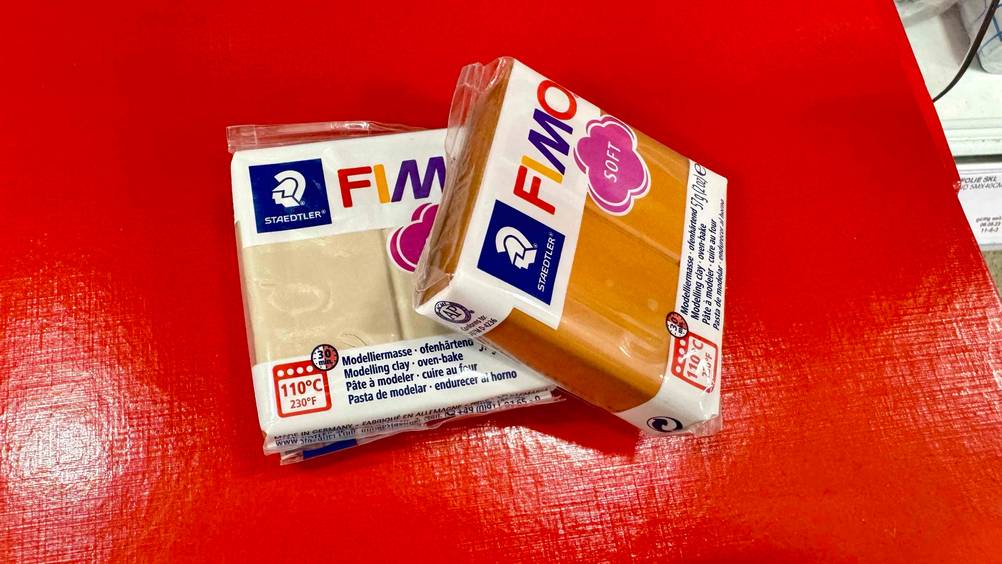 Auf einer roten Fläche liegen zwei Packungen der getesteten Modelliermasse leicht übereinander.