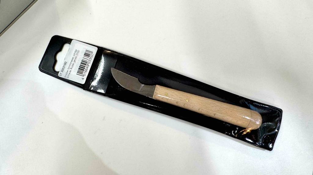 Das getestete Schnitzmesser inklusive transparenter Verpackung liegt auf einer weißen Oberfläche.